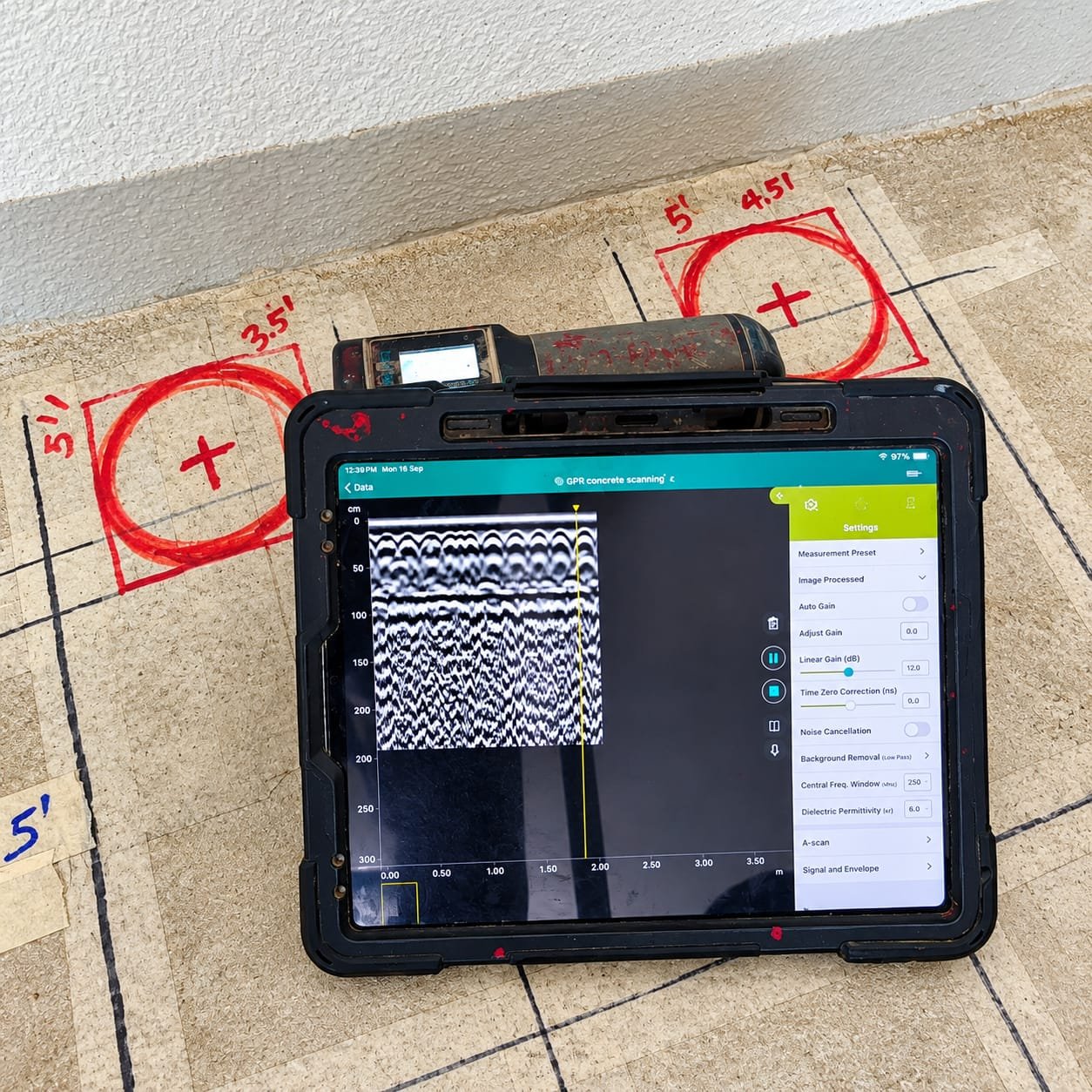 GPR concrete scanning tablet locating rebar and post-tension cables on a marked slab before core cutting in Dubai UAE
